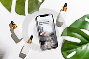 Design of the smartphone screen, Application of cosmetics online. White serum bottle and cream jar, mockup of beauty product brand