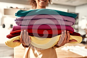 From design to delivery. Cropped shot of woman holding stack of colorful sweatshirts, hoodies while standing in the