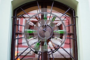 Design of a window grill with a rounded clock made with bottles in Cesky Krumlov, Czech Republic