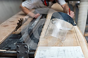 Design wood concept. Photo of transparent protective face mask lying on the stack of lumber with blurred table saw handcraft