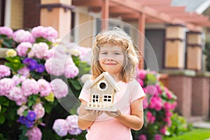 Design of your dream house. Kid playing with small house model outdoors at home garden.