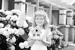 Design of your dream house. Kid playing with small house model outdoors at home garden.