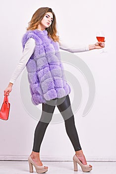 Designer clothing luxury fashion boutique. Woman with handbag hold glass of wine. Girl wear fashion fur vest while