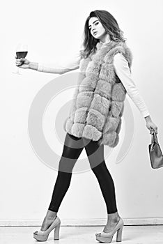 Designer clothing luxury fashion boutique. Woman with handbag hold glass of wine. Girl wear fashion fur vest while