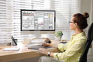 Designer creating website on computer at wooden table