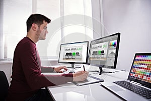 Designer Drawing On Graphic Tablet While Working On Computer