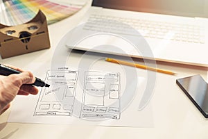 Designer drawing website development wireframe on paper