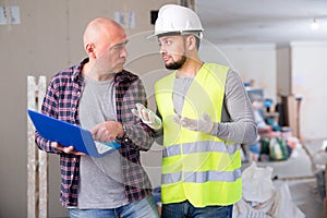 Designer and foreman talking about work in construction site