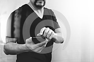 Designer hand using smart phone for mobile payments online shopping,omni channel,on white background,black white,front view