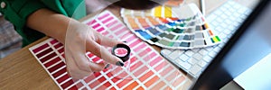 Designer looks through magnifying glass at samples of colors and shades of red on paper palette