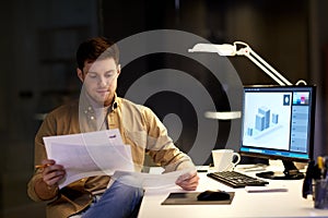 Designer with papers working at night office