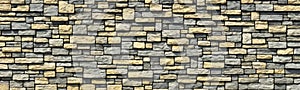 Designer stacked cream slate stones to create textured and rough feature wall. Warm and plain brown pattern repeats horizontally.