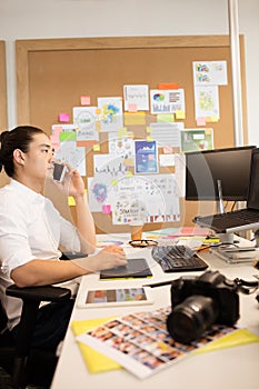 Designer talking on phone while working in creative office