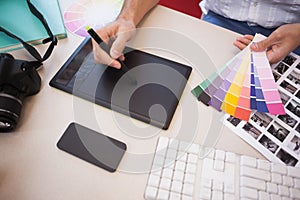 Designer using graphics tablet and colour charts