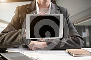 Designer using tablet with laptop and document on desk in the morning.