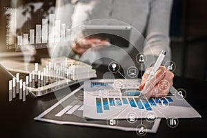 Designer using tablet with laptop and document on desk in office.