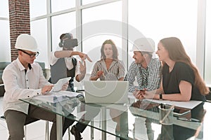 Designer wearing virtual reality glasses at a meeting with the business team