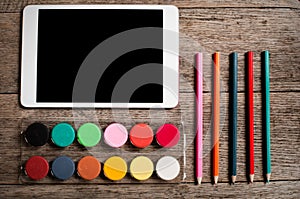 A designers tablet seen from above with a paint palette and colouring pencils