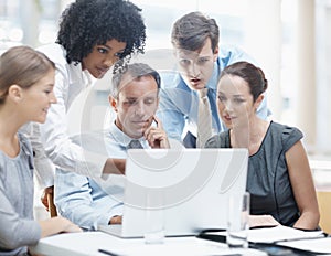 Designing the new website. A multi-ethnic group of business people sitting around a laptop during a meeting.