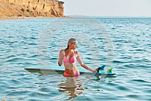 Desire of adventure, summer time and time to relax idea. Lady on vacation with surfboard posing on mountain background.