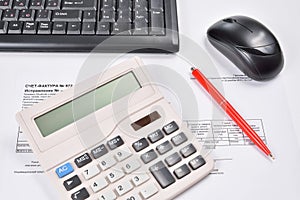 Desk accountant closeup: invoice, keyboard, calculator, mouse, and red pen