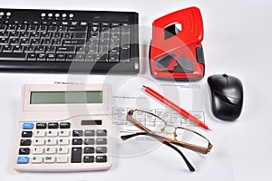 On the Desk of the accountant: invoice, keyboard, calculator, mouse, hole punch, glasses and red pen