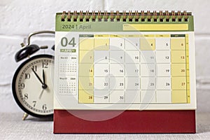 Desk calendar for April 2024 and a clock on the table