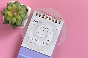 Desk calendar for July 2024 on a pink background with copy space