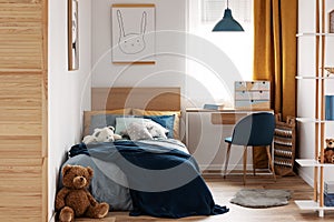 Desk, chair and single bed with blue bedding in cozy bedroom interior for children