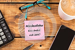 Desk with german text mindestlohn Was ÃÂ¤ndert sich 2019, in english minimum wage, what will change 2019
