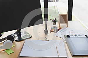 desk of graphic designer at work - digital tablet, computer screen, color swatch catalog samples for selection. Creativity Editor