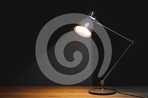 Desk lamp with spotlight, black background with copy-space