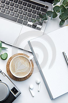 Desk with laptop, coffee, notebook and camera