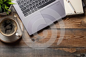 Desk with laptop, eye glasses, notepad, pen and a cup of coffee on a old wooden table. Top view with copy space. Flat lay. Dark ba