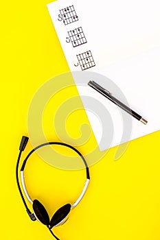 Desk of musician for songwriter work with headphones and notes yellow background top view