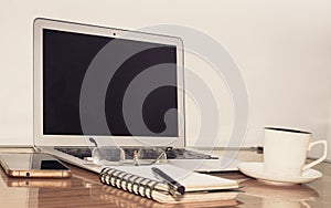 Desk with open notebook, mobile phone, eye glasses, pen and a cup of coffee. Top view with copy space. Business still life concept