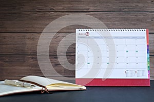 Desk standing calendar with notepad against wooden wall
