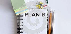 Desk with stationary and notebook with text Plan B and pen, pencil, stickers