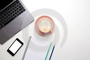 Desk top laptop computer ,Mobile phone blank white mockup,Coffee cup, Pen and note paper on white table. Copy space for your text