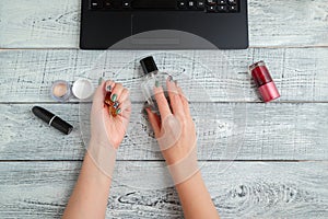 Desk. woman`s workplace. women`s hands,laptop,perfume and cosmetics. the view from the top. flat lay