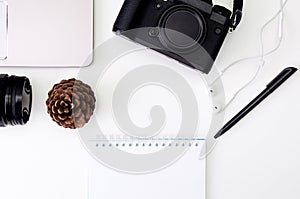 Desk workspace with laptop keyboard, hipster camera, lens, notepad for writing with black pen on white background. flat