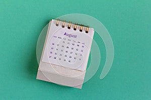 Desktop calendar for August 2023 on a green background.