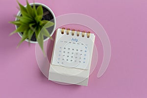 Desktop calendar for July 2023 on a pink background.