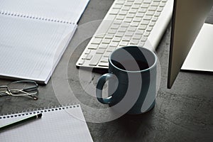 Desktop computer, cup of coffee and note pad on the office desk