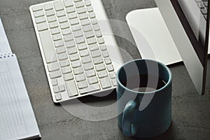 Desktop computer, cup of coffee and note pad on the office desk