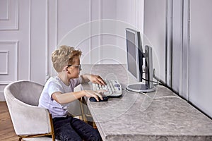 Desktop computer with little boy during e-learning during pandemic.