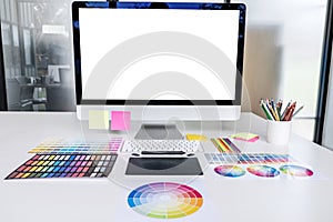 Desktop computer screen on white desk, Graphic designer and color swatch samples at workplace