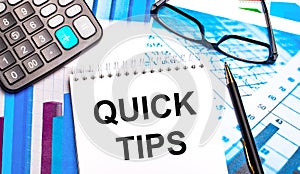 The desktop contains colored tables, a calculator, glasses, a pen and a notebook with the text QUICK TIPS
