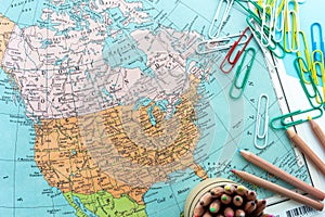 Desktop design with map of Canada and America with colorful paperclips and colored pencils