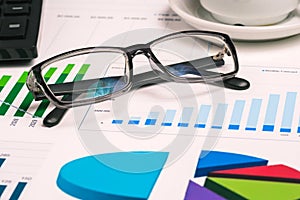 Desktop with documents, charts, a calculator, and black-rimmed glasses. Market analysis and financial report. Business concept